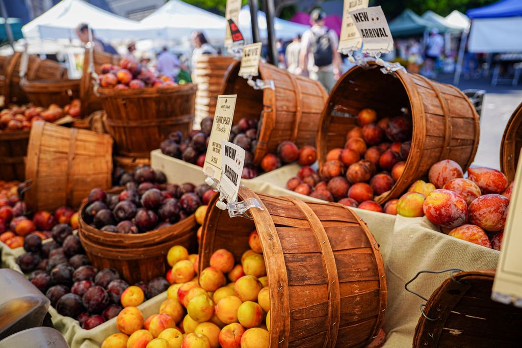 Colorful display of fresh fruits in wooden baskets at an outdoor farmers market.