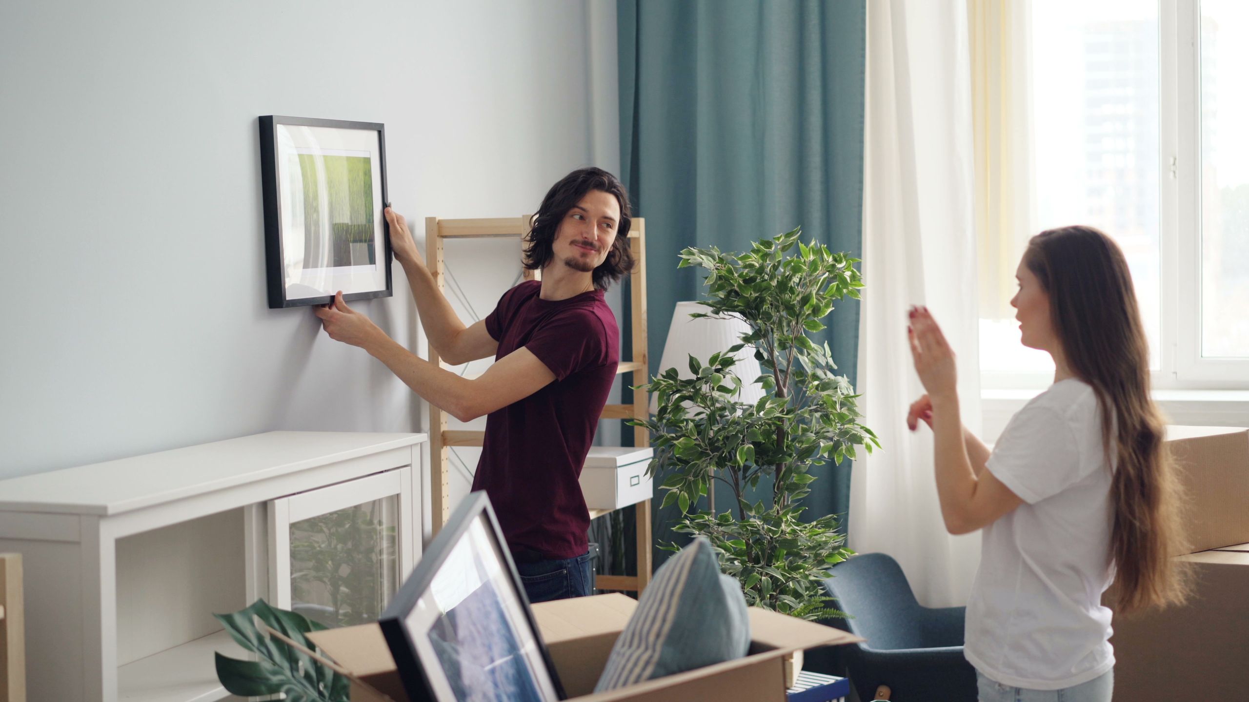 Couple arranging a framed picture in their living room during a move-in.