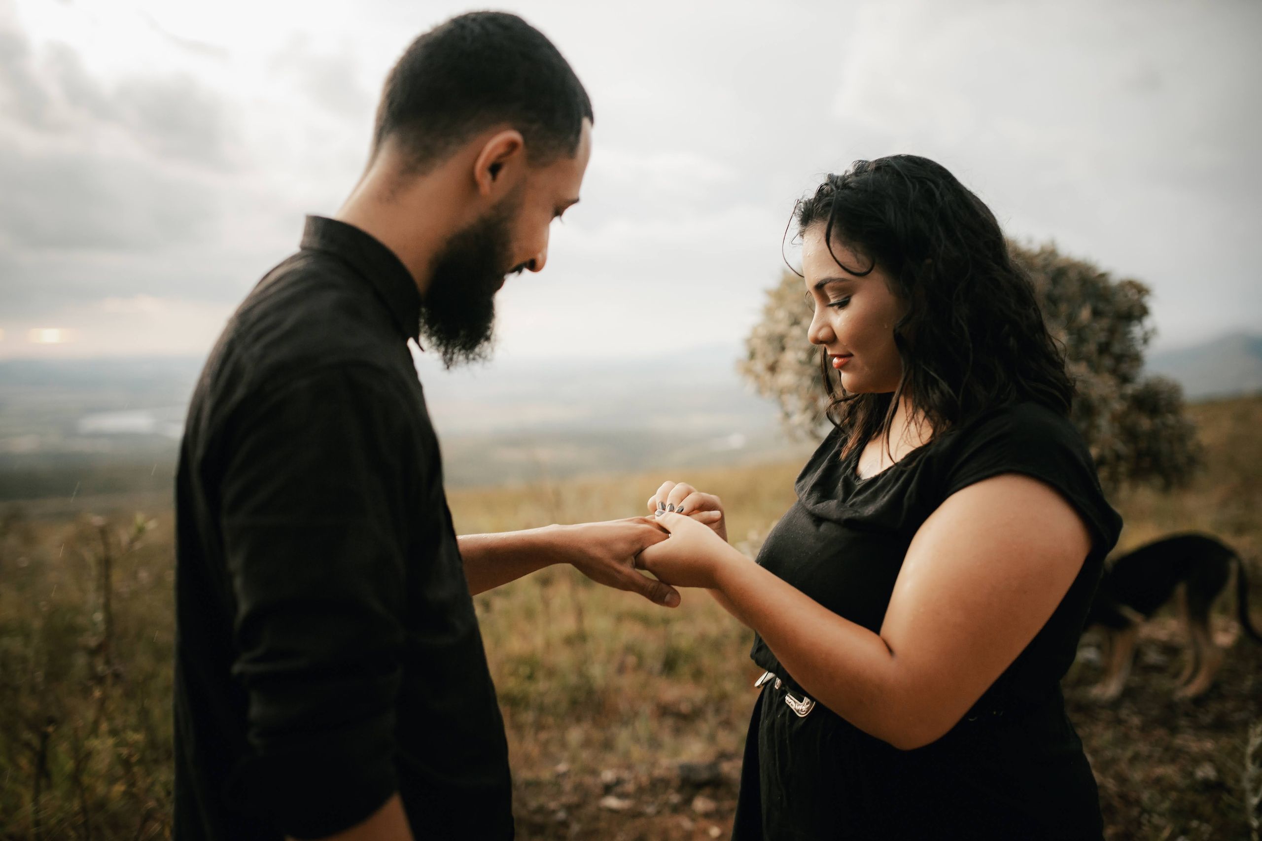 Couple celebrating engagement outdoors with scenic backdrop.
