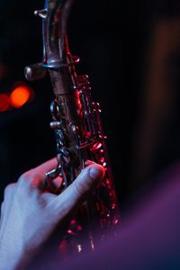 Detailed close-up of a hand gripping a saxophone with dramatic lighting, highlighting the brass instrument.