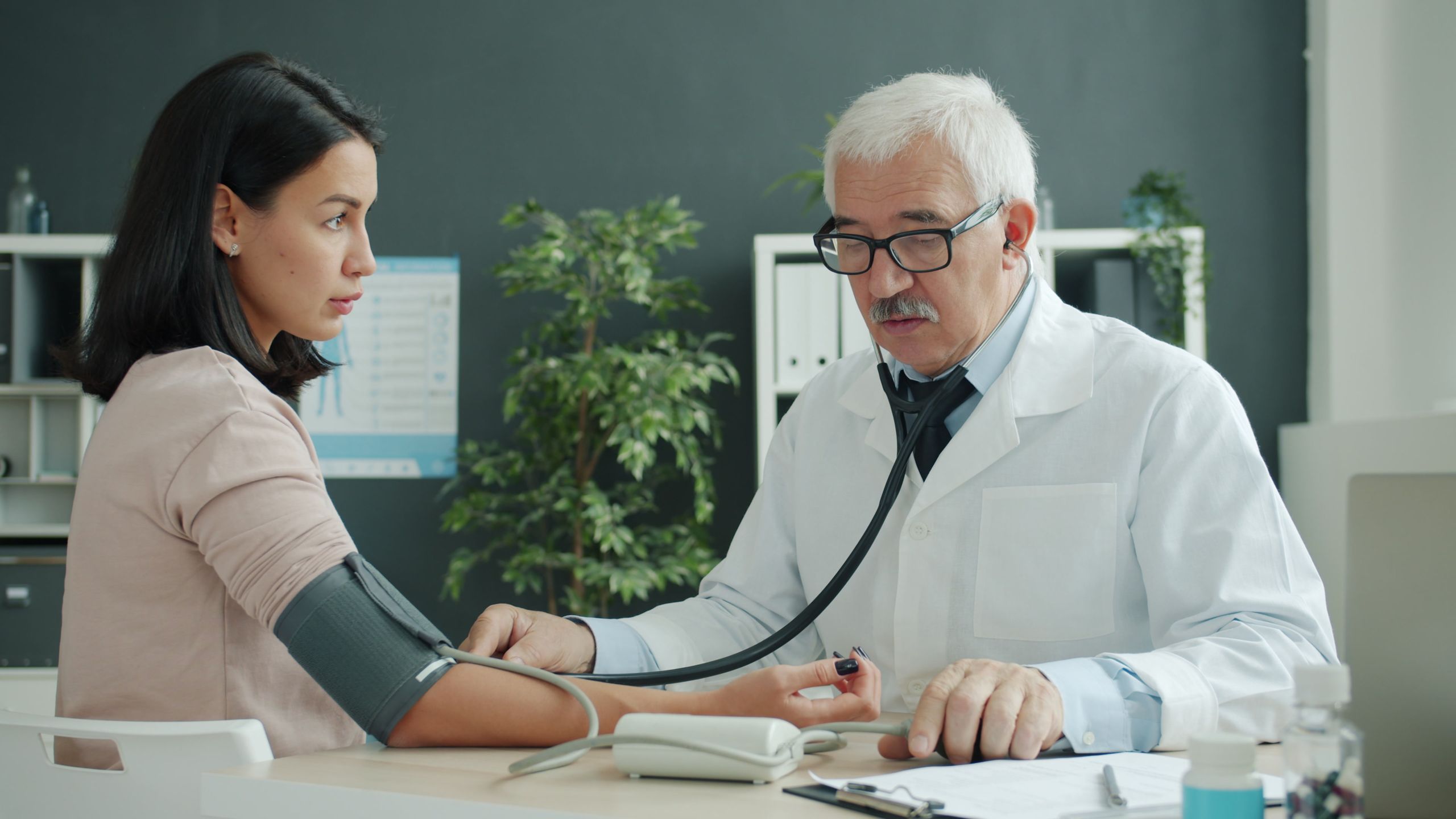 Doctor checking blood pressure of patient at medical clinic.