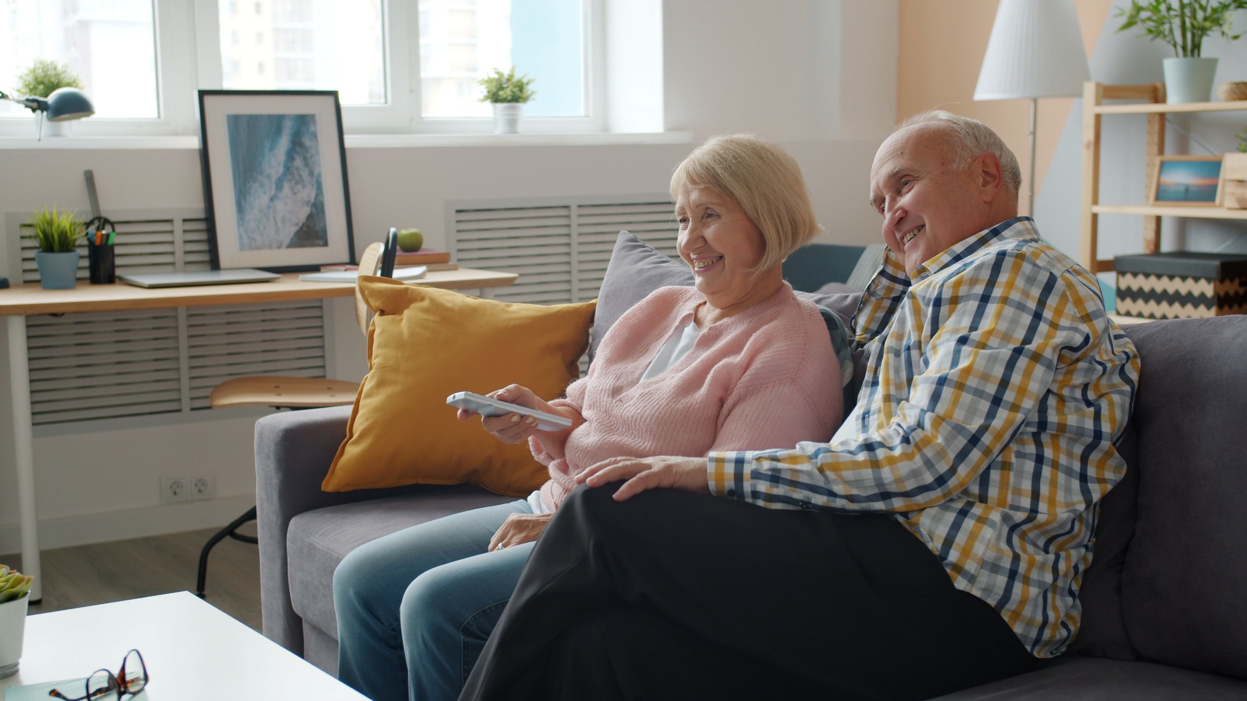 Elderly couple smiling and enjoying time together on a cozy living room sofa.
