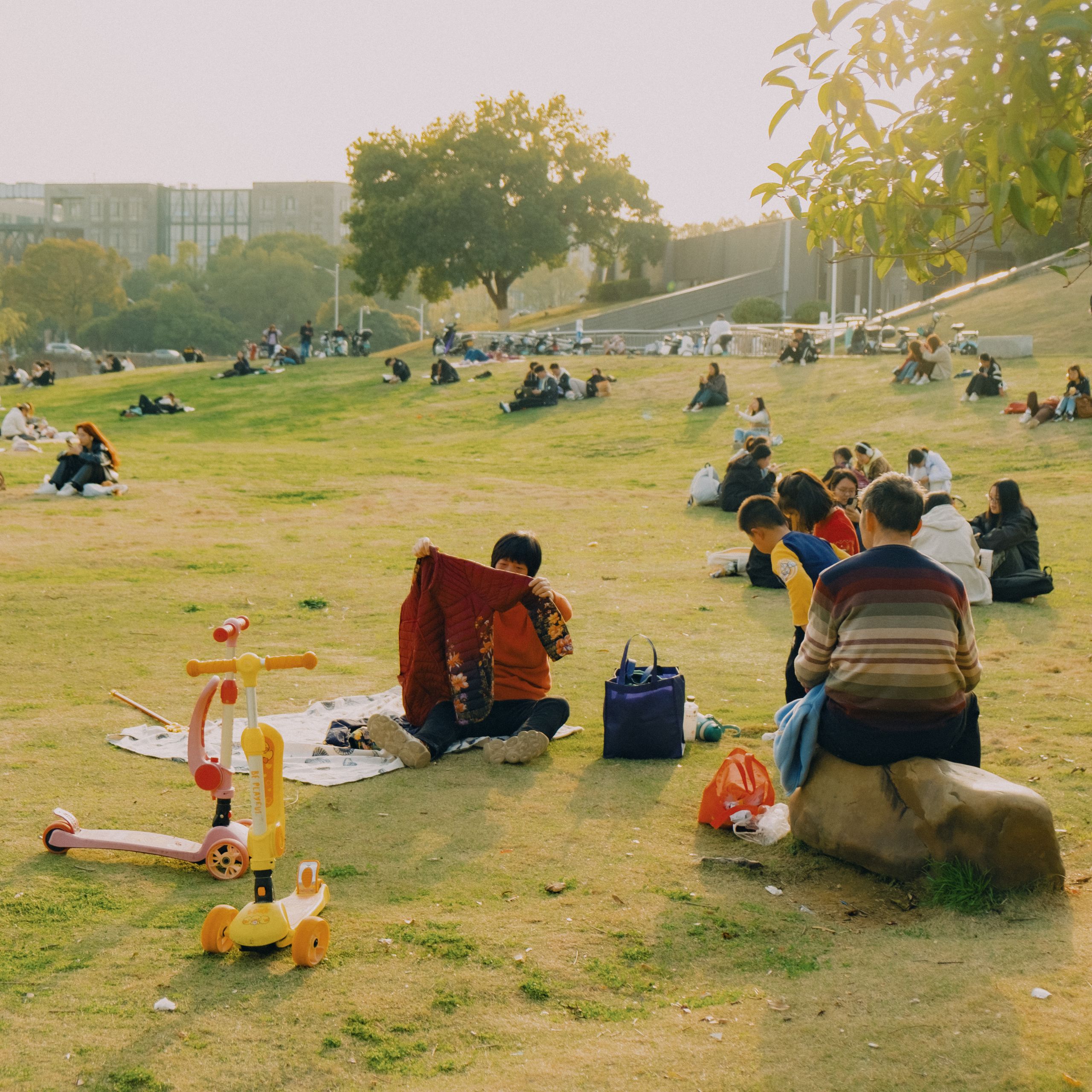 People enjoying a sunny day outdoors with family activities in a city park.