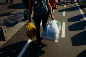 high-angle-shot-of-a-person-walking-on-the-sidewalk-while-carrying-plastic-bags-