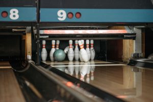 white-and-red-bowling-pins-with-green-bowling-ball-