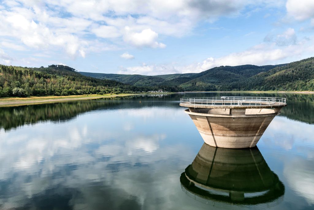 Picturesque landscape with reflective lake and overflow structure in Langelsheim, Germany.