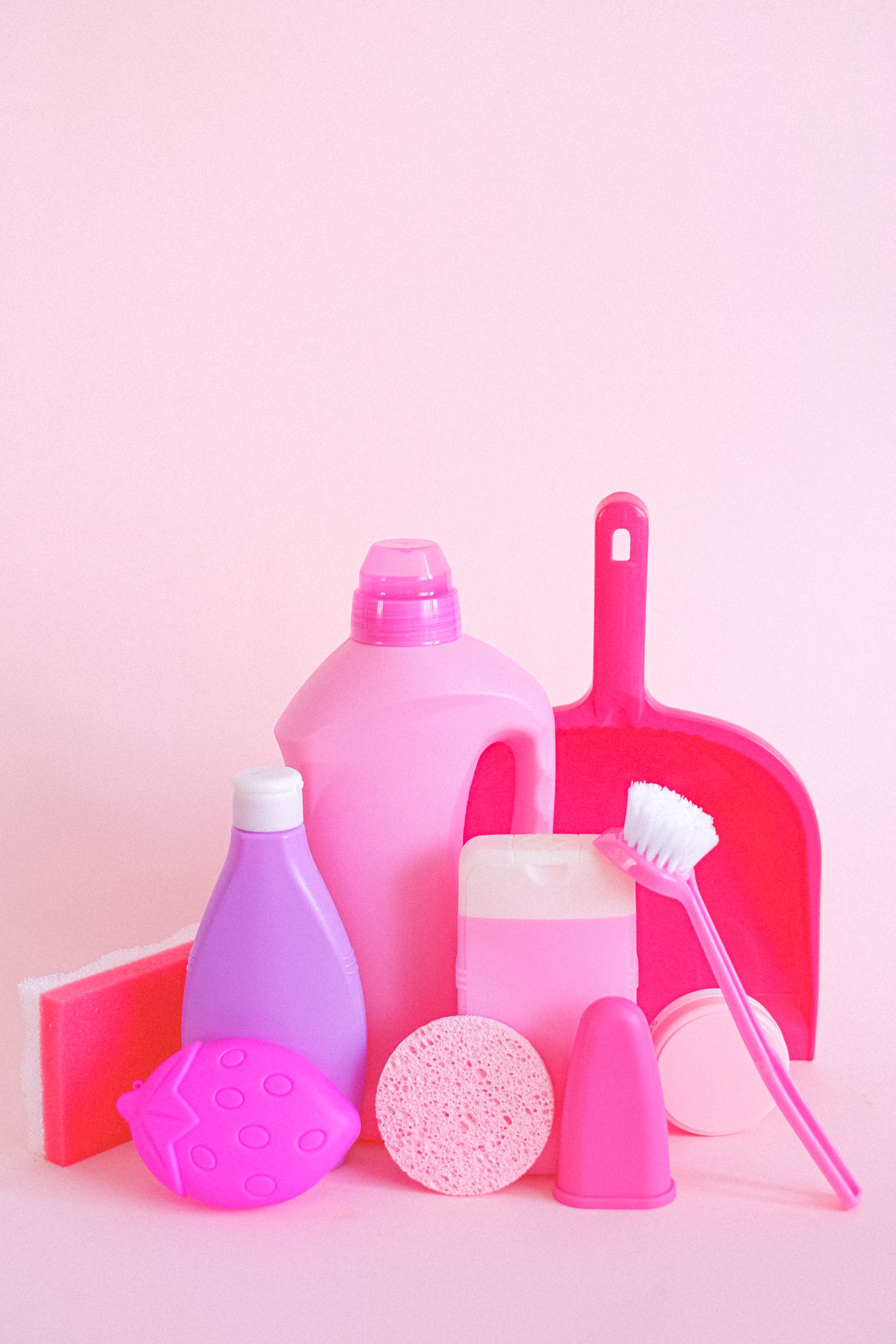Plastic bottles filled with detergent placed near sponge and brush with dustpan for hygiene routine
