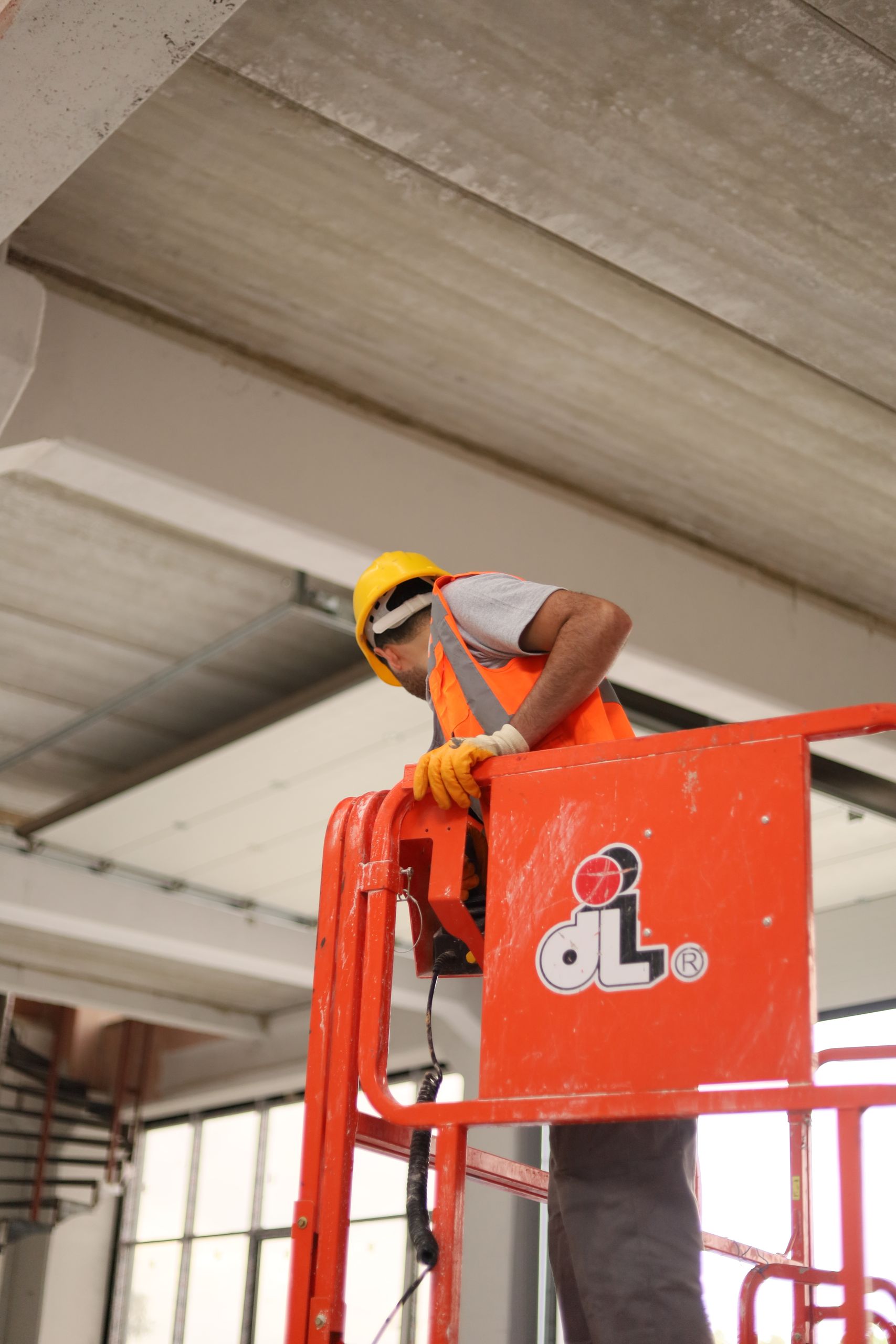 Safety-conscious worker using cherry picker in an indoor construction site.