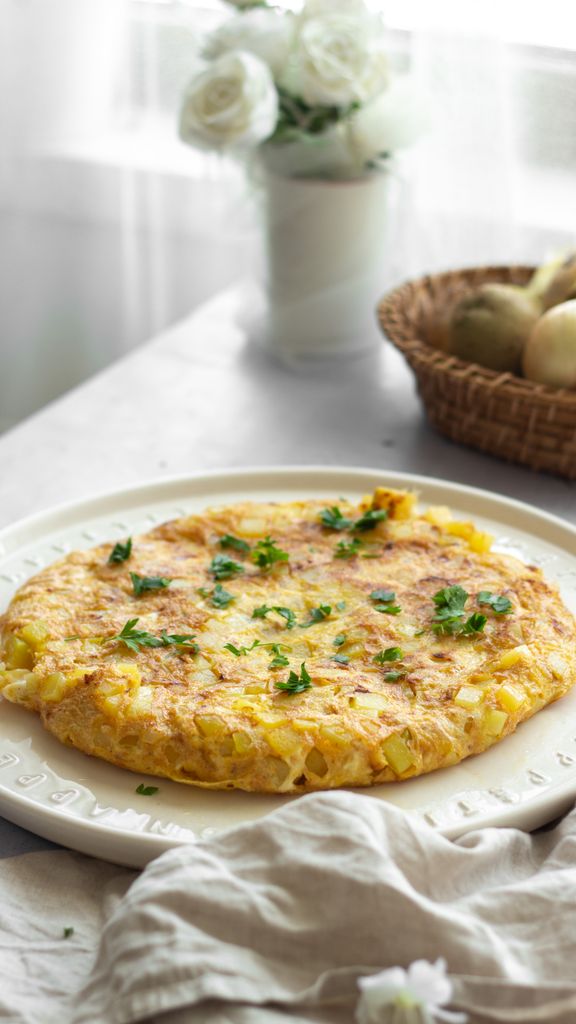 Spanish tortilla garnished with parsley on a plate in a cozy setting.