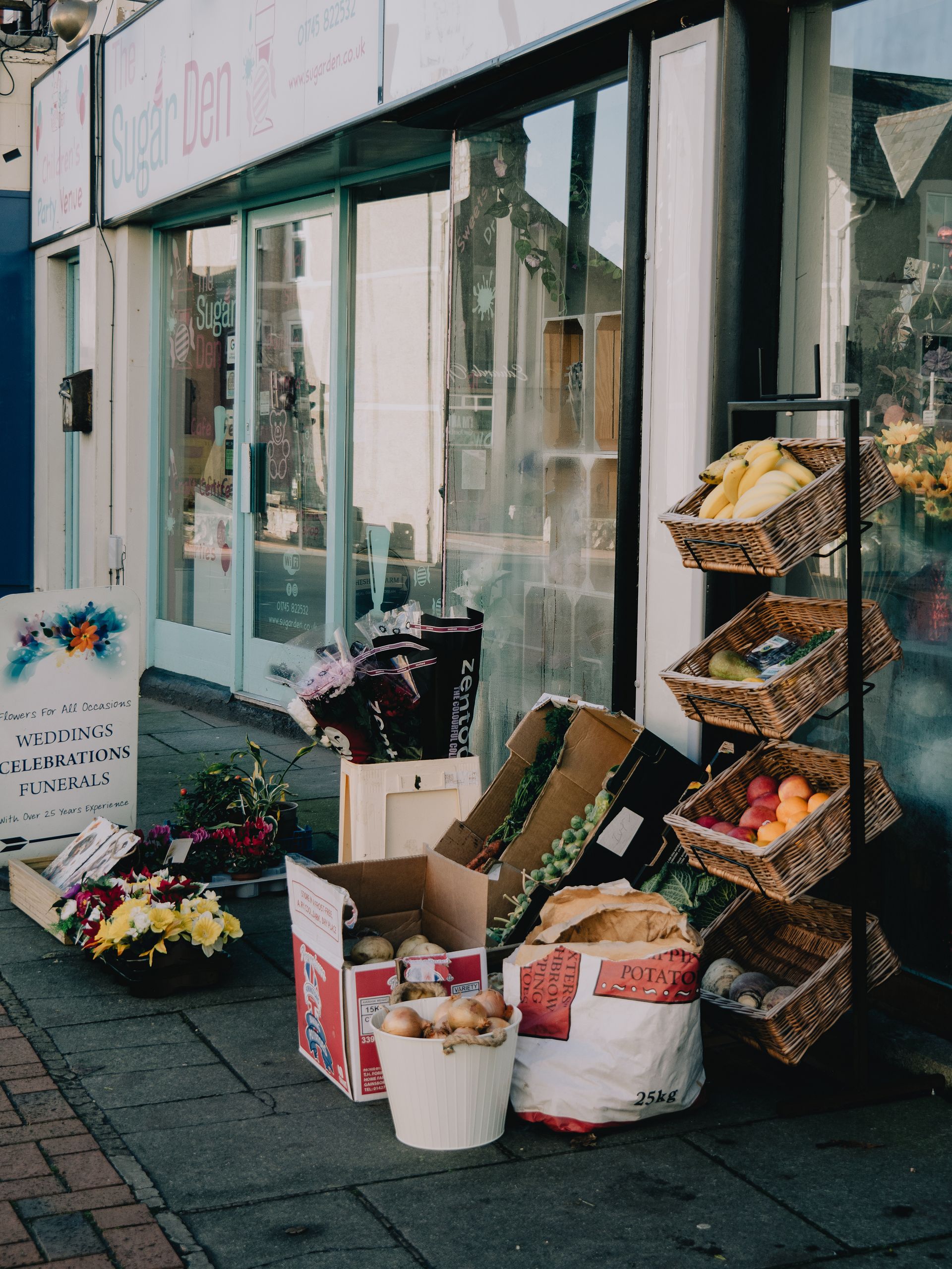 Street scene featuring fresh produce and floral arrangements outside an urban market.