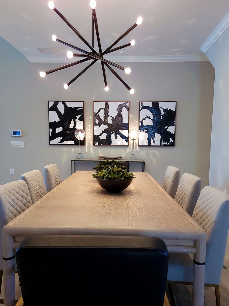 Stylish dining room featuring abstract art, a sleek chandelier, and a wooden table with plush seating.