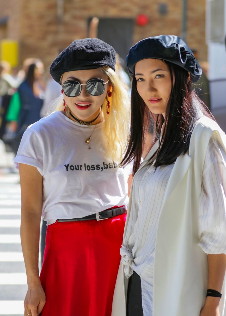 Two stylish women in berets showcasing urban fashion on a sunny street.