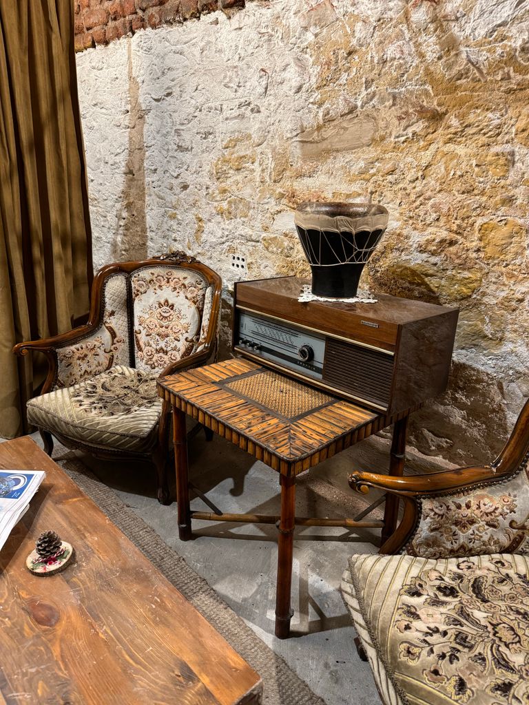 Vintage living room featuring retro radio, ornate armchairs, and cozy decor.