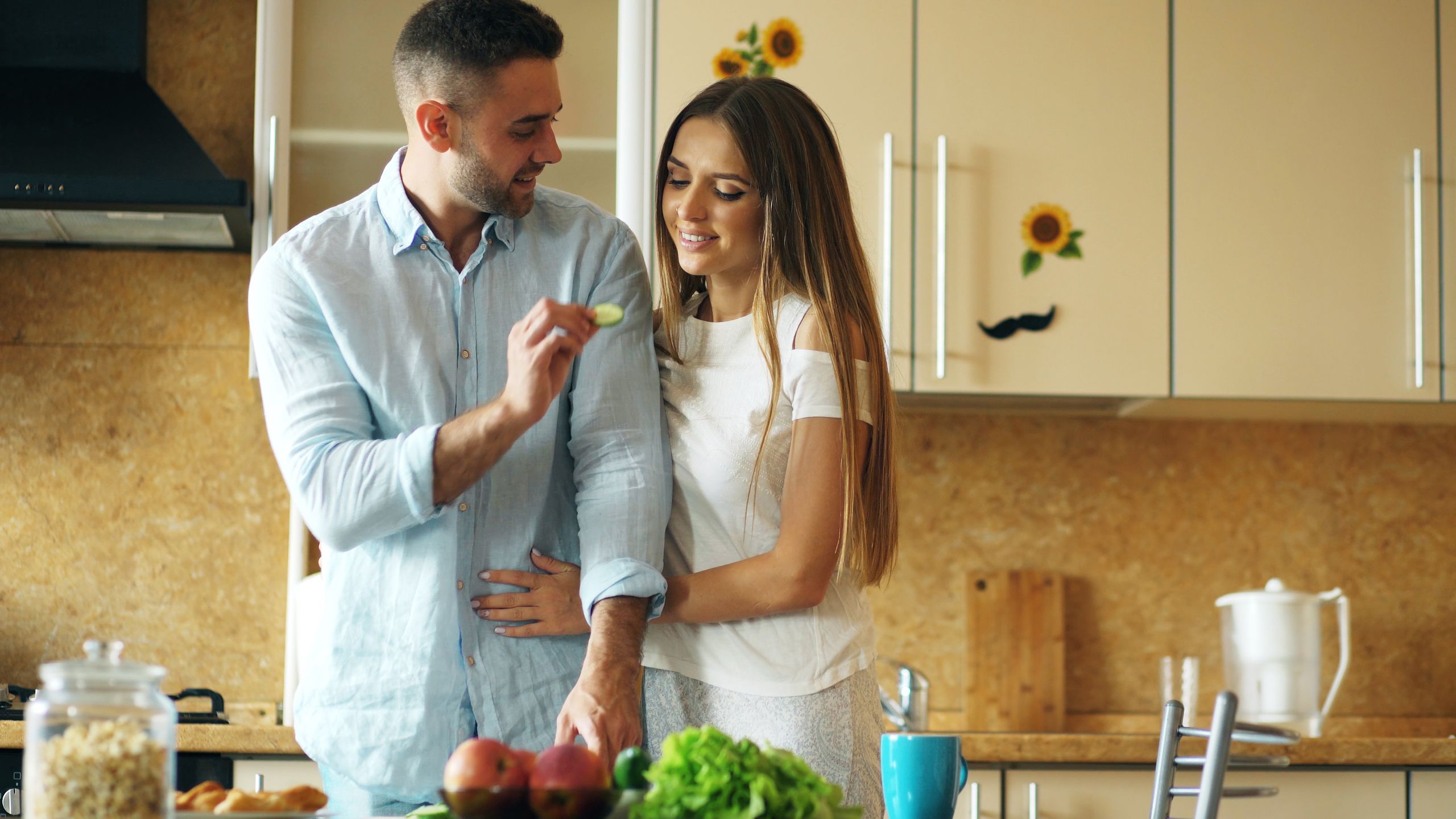 Young couple enjoying time cooking fresh meal in cozy kitchen setting, highlighting relationship and healthy lifestyle.