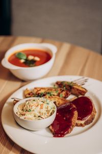 A hearty meal featuring tomato soup, meatloaf with sauce, seasoned wedges, and coleslaw.